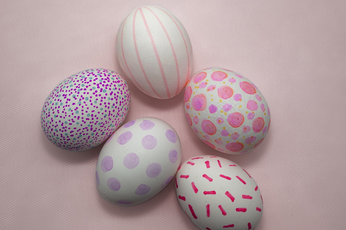 Five decorated easter eggs on a pink background