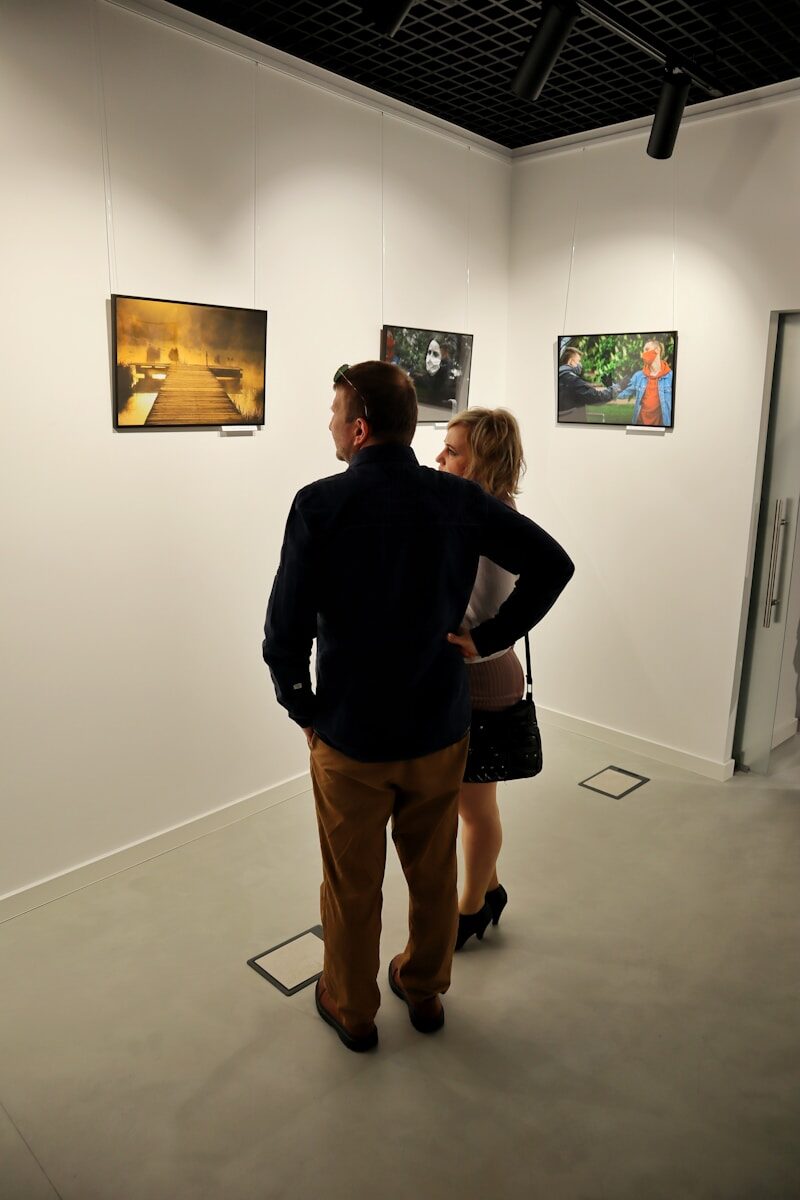 A man and a woman looking at pictures on the wall